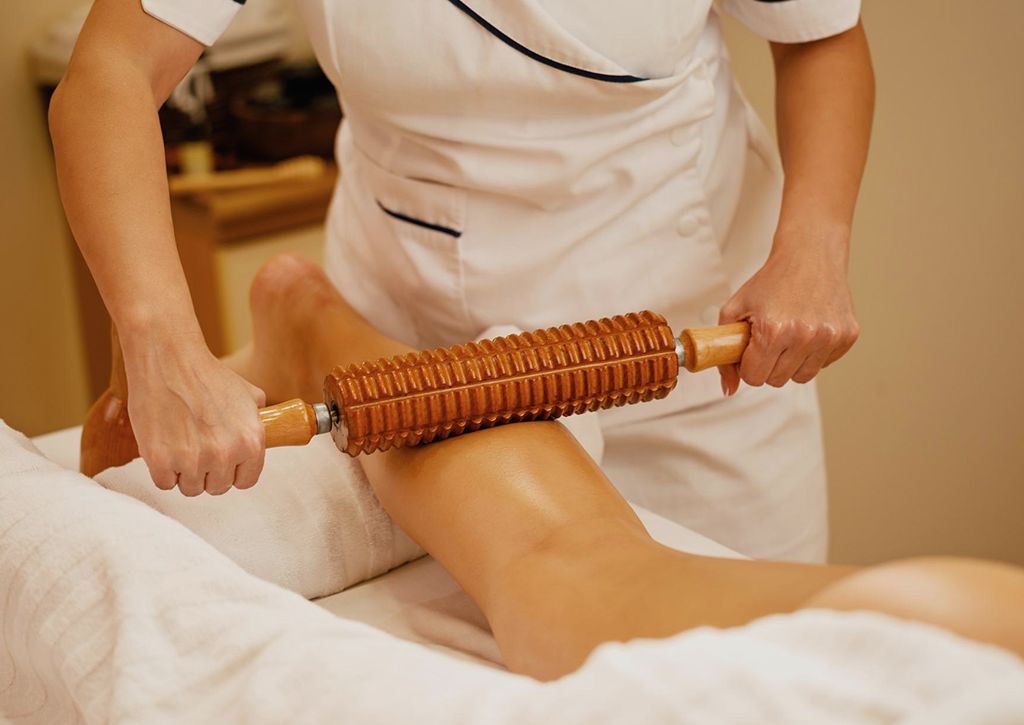 Therapist performing Wood Therapy treatment on client’s body to sculpt and contour