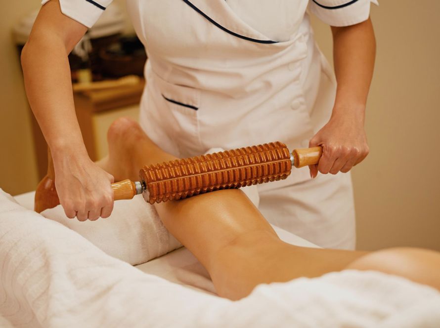 Therapist performing Wood Therapy treatment on client’s body to sculpt and contour